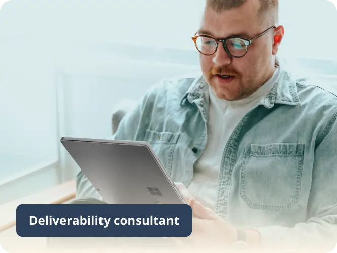 Lista negra SURBL: Cómo eliminar tu IP de ella 6 A person with glasses and a mustache is sitting on a chair, holding and looking at a Surface laptop. They are wearing a light-colored shirt and denim jacket. A caption reads Deliverability consultant.